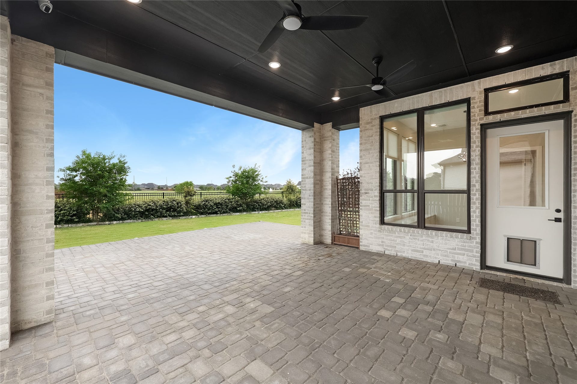 6707 Nimitz Court, Katy, TX 77493 Extended covered patio with brick paver flooring and ceiling fans, creating a comfortable outdoor living space ideal for entertaining year-round. Water piped for outdoor kitchen.