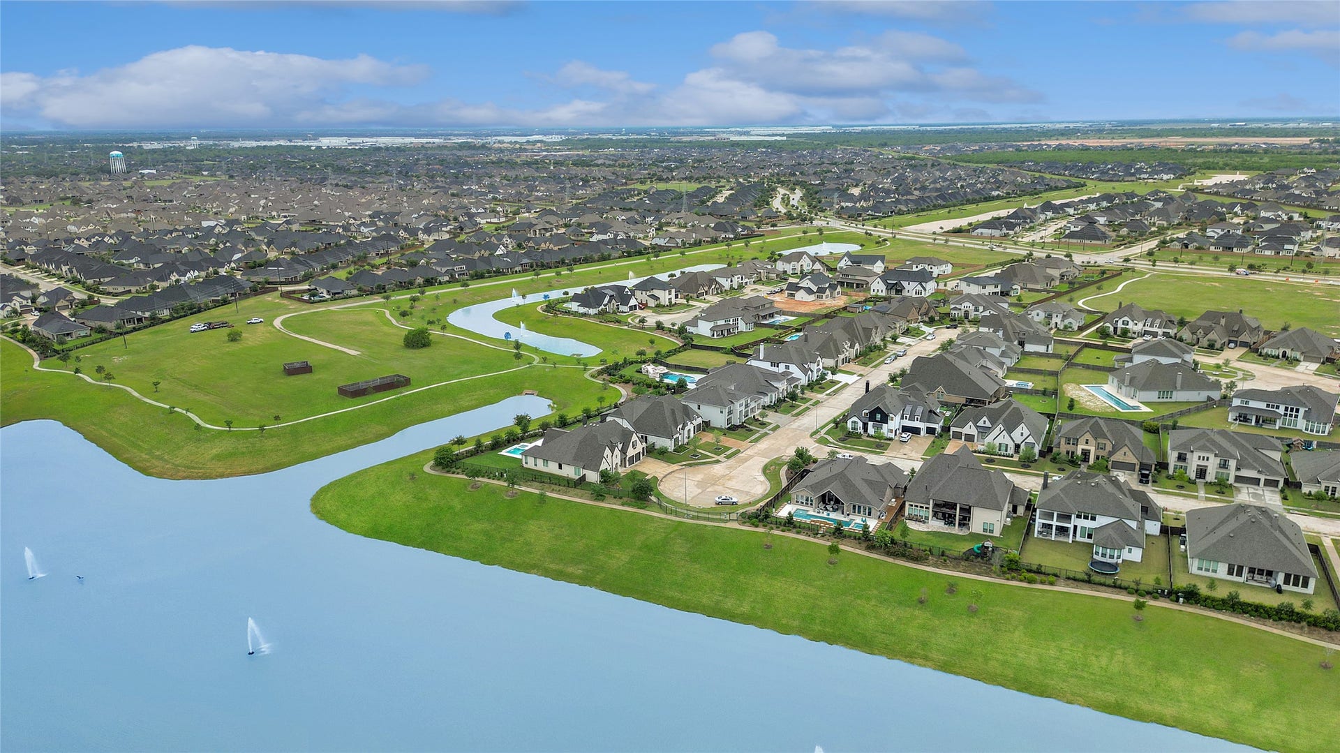 6707 Nimitz Court, Katy, TX 77493 Sweeping aerial capturing the broader neighborhood layout with multiple water features, landscaped common areas, and nearby homes.