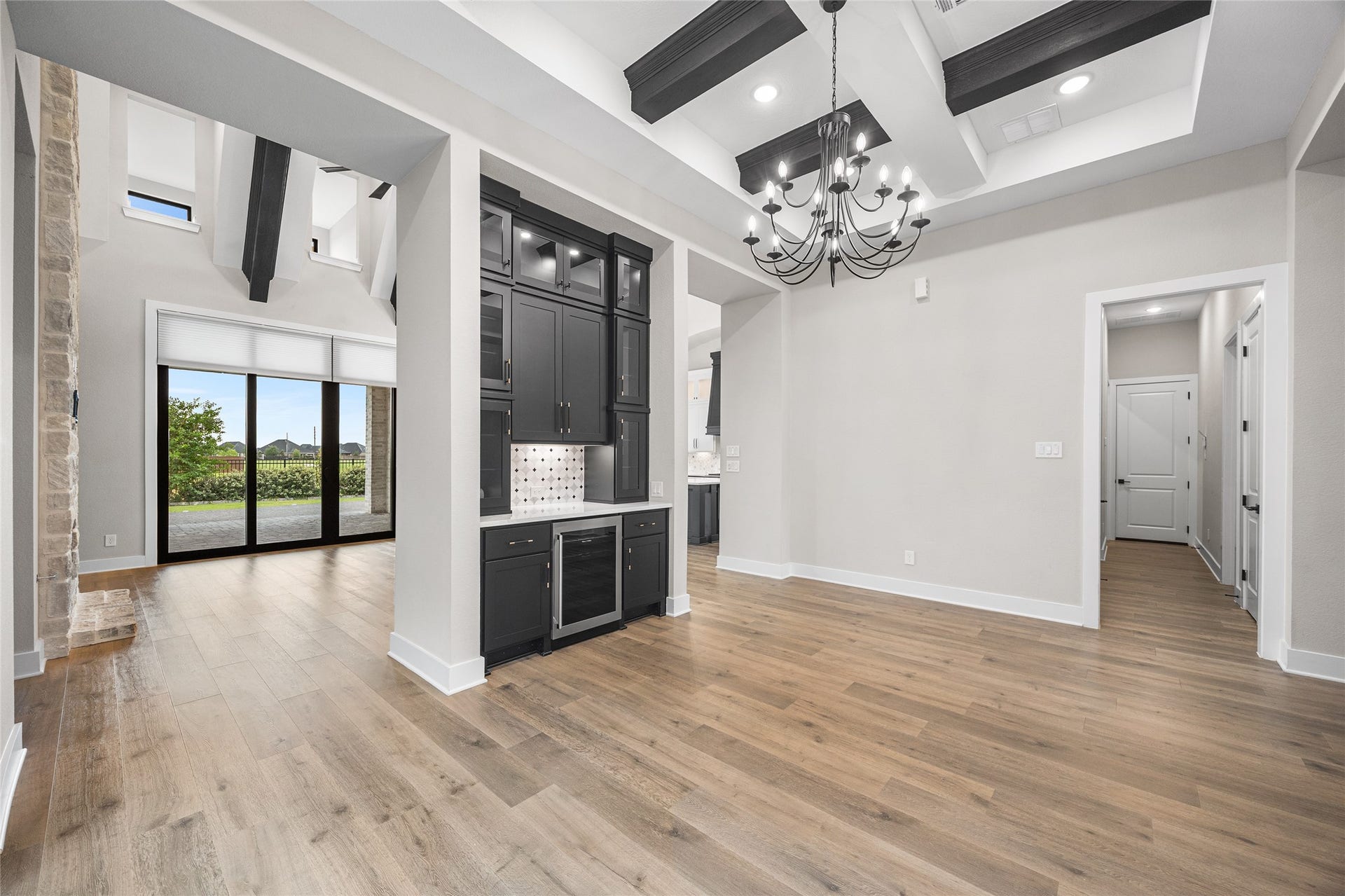 6707 Nimitz Court, Katy, TX 77493 Expansive dining area with soaring ceilings, dramatic exposed beams, and a floor-to-ceiling stone fireplace, complemented by large sliding glass doors that open to the covered patio.