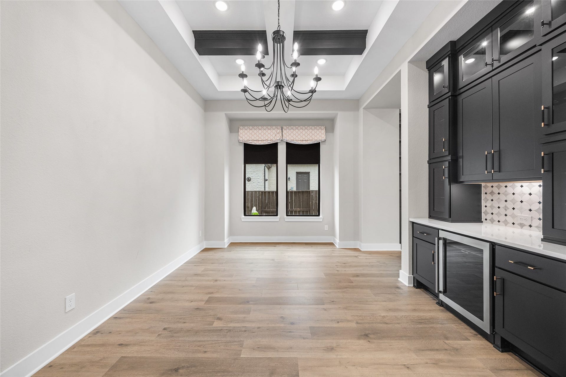 6707 Nimitz Court, Katy, TX 77493 Grand dining space featuring a tray ceiling with exposed beams and a statement chandelier, offering a refined setting for gatherings and everyday meals.