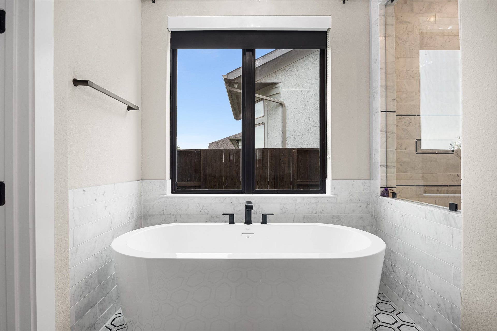 6707 Nimitz Court, Katy, TX 77493 Freestanding tub positioned beneath a large window, offering a relaxing setting with natural light and serene backyard views.