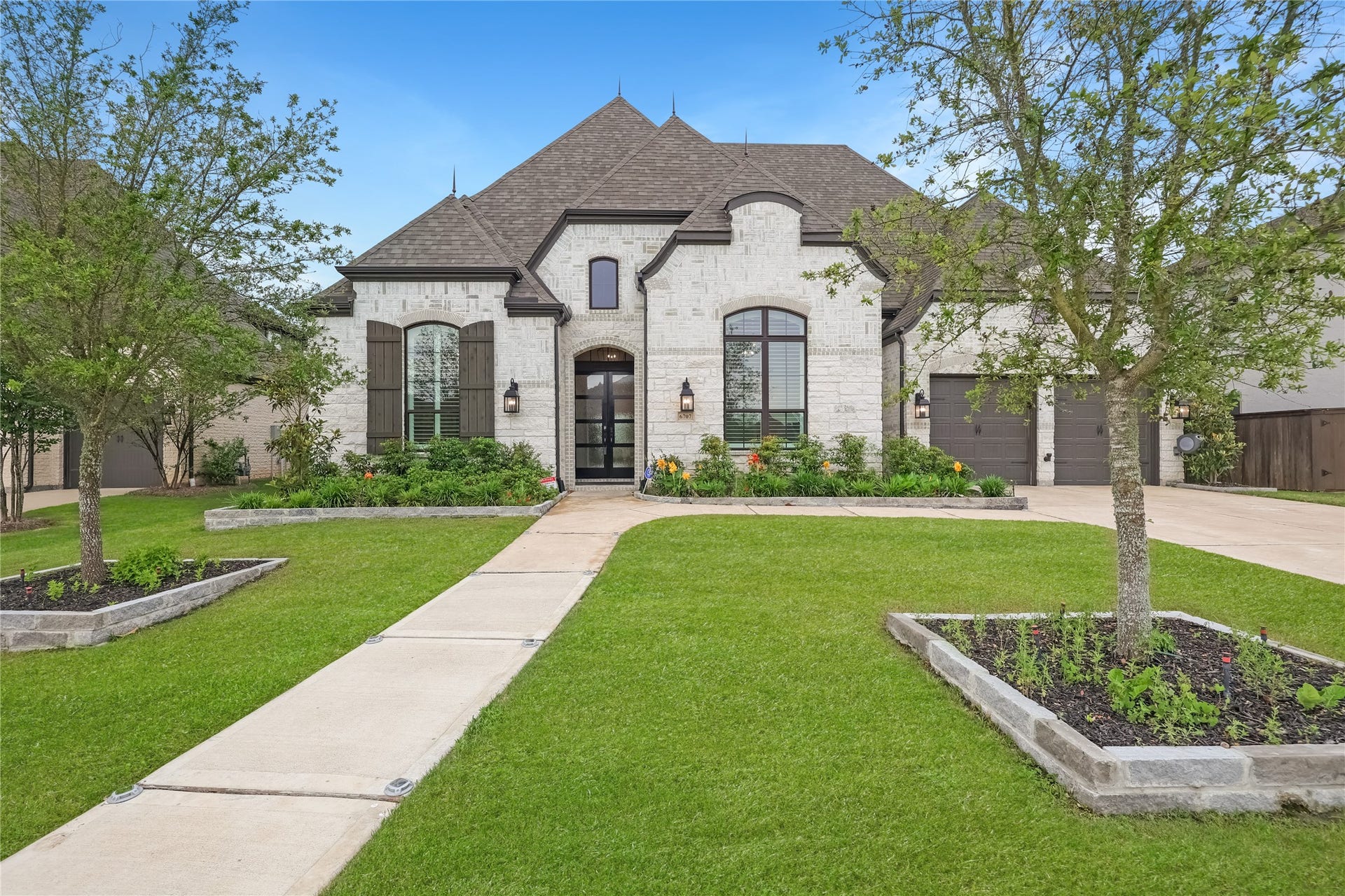 6707 Nimitz Court, Katy, TX 77493 Striking stone faade with arched architectural details, dark shutters, and a welcoming entry framed by manicured landscaping.