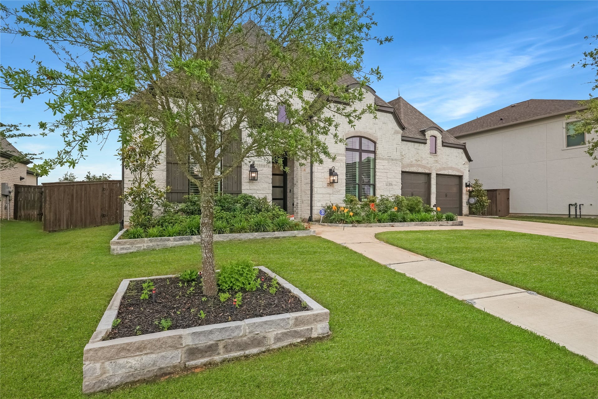6707 Nimitz Court, Katy, TX 77493 Beautifully landscaped front elevation with mature greenery, stone faade, and inviting entryway that delivers strong curb appeal.