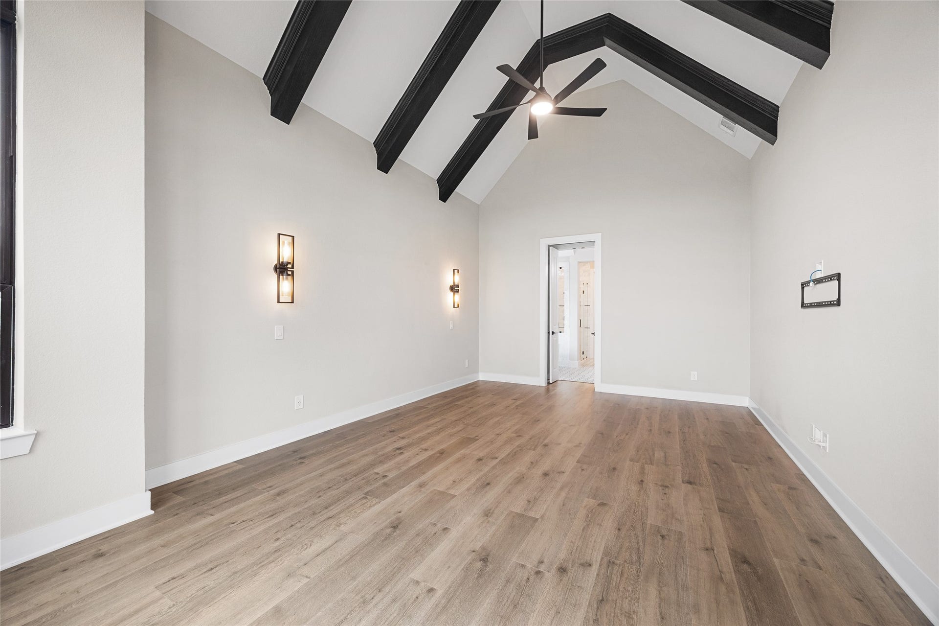 6707 Nimitz Court, Katy, TX 77493 Generous layout with modern ceiling fan and wall sconces, offering flexibility for a variety of furniture arrangements and a seamless connection to the en-suite bath.
