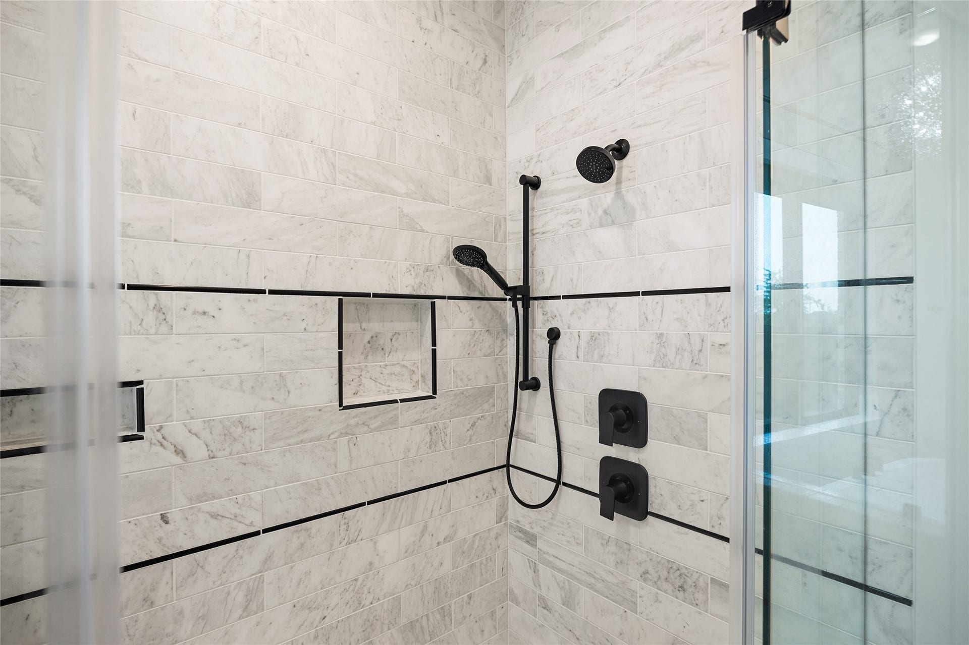 6707 Nimitz Court, Katy, TX 77493 Designer walk-in shower with marble-look tile, built-in niche, and sleek black fixtures for a clean, contemporary finish.