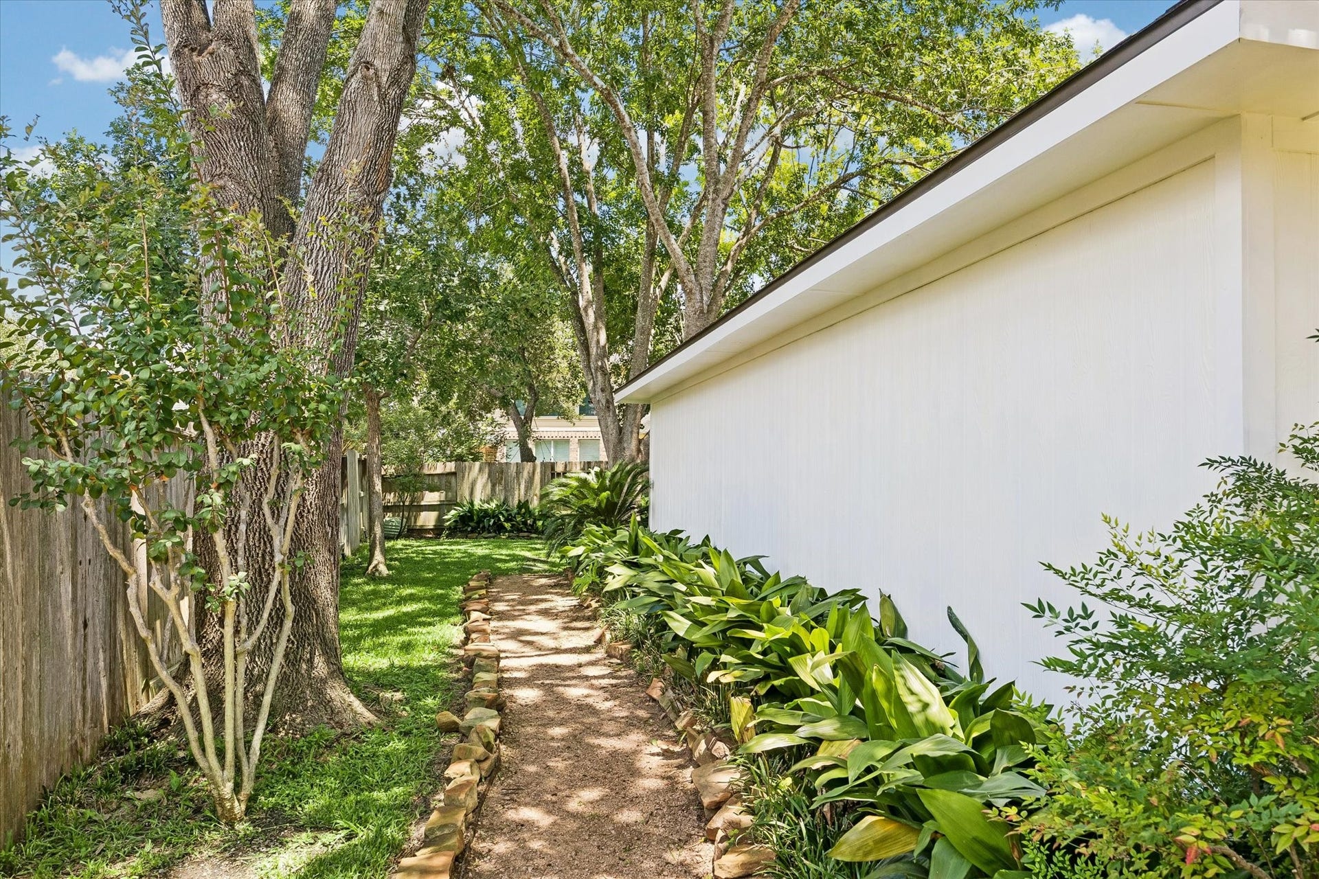 7535 Guinevere Drive, Sugar Land, TX 77479 A winding garden path leads through a peaceful, tree-shaded side yard