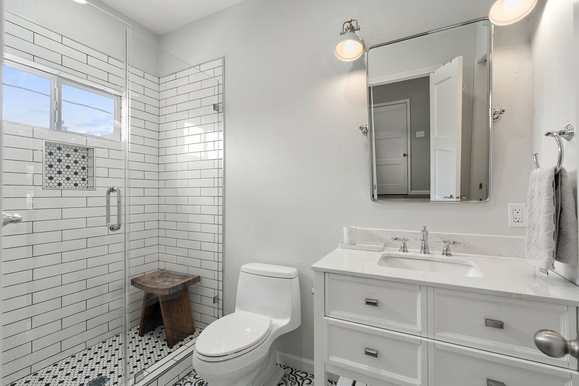 919 Ashland Street, #A, Houston, TX 77008 GARAGE APARTMENT full bath features a frameless walk-in shower w/ white subway tile surround, decorative tile flooring + high privacy window. Vanity w/ storage, mirror & lighting complete the space.