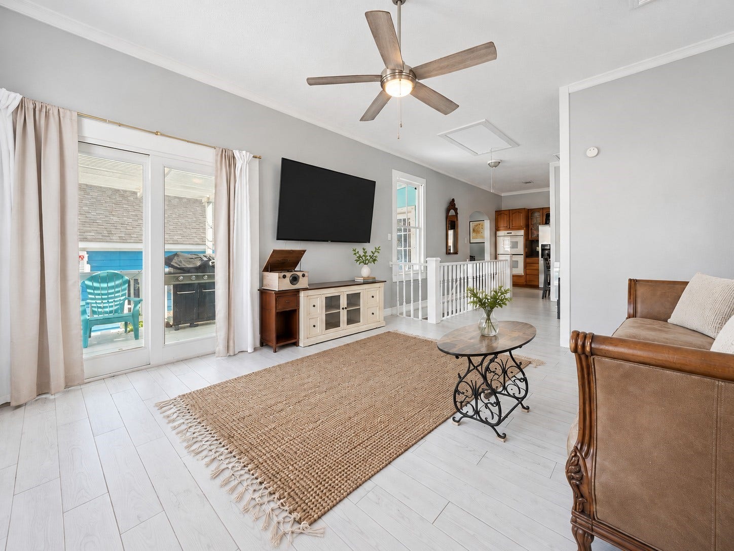 1805 19th Street, Galveston, TX 77550 Second-Floor Living Area with Kitchen View: Designed for comfort, versatility, and effortless coastal living! This spacious second-floor living area offers an inviting space for relaxing, entertaining, or gathering with vacation guests. Features abundant natural light, wood-look tile flooring, an open layout connecting to the kitchen, and French doors leading to the upper deck for seamless indoor-outdoor enjoyment.