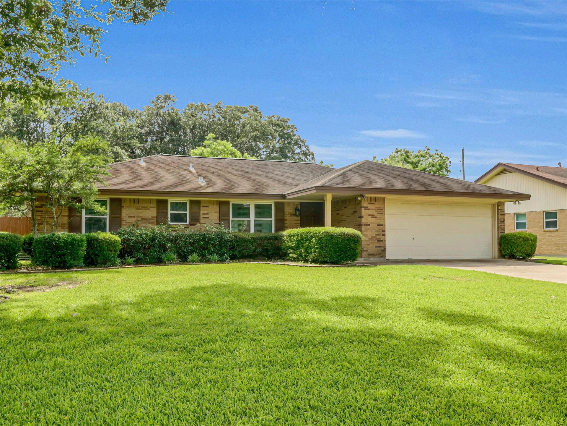 805 Bluebonnet Lane, Katy, TX 77493 Charming single-story home with a classic brick exterior, lush green lawn, and a spacious attached garage.