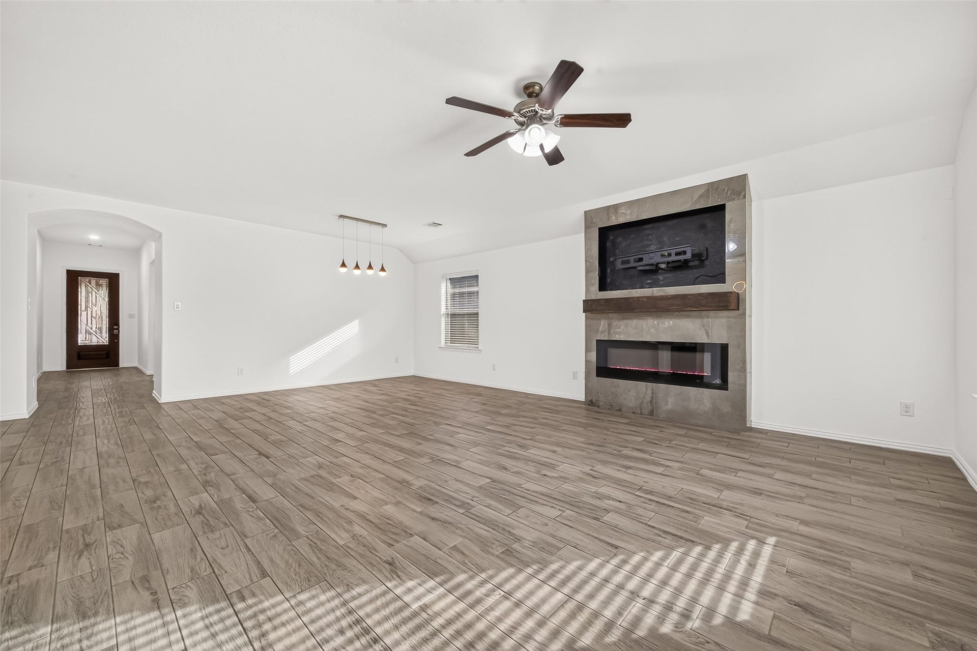 19711 Lakeside Pointe, Richmond, TX 77407 Soaring ceilings, wood-look tile flooring, and a striking fireplace create an inviting gathering space, with an adjoining dining area perfect for everyday meals or hosting guests
