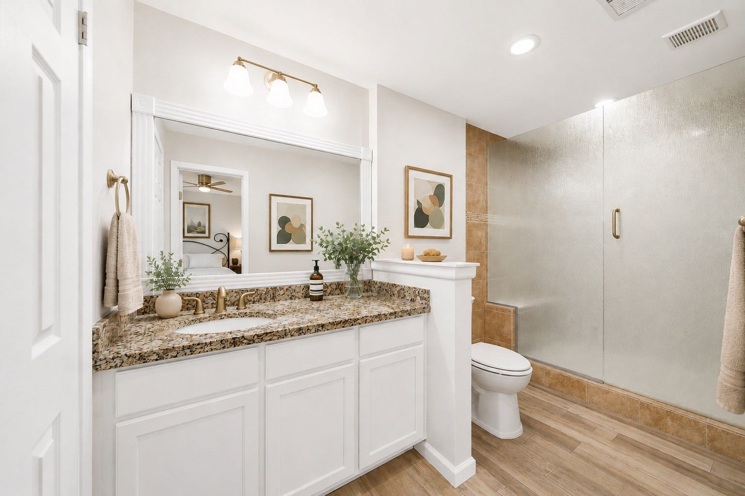 The spacious primary bathroom offers a bright, timeless design with an oversized granite vanity, generous counter space, and a large framed mirror. A walk-in glass-enclosed shower, neutral finishes, and direct access to the primary suite create a comfortable, spa-like retreat perfect for everyday living.