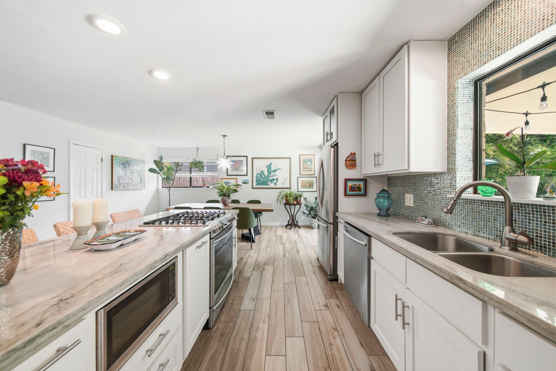 This spacious kitchen features white cabinets, upgraded countertops, stainless steel appliances and modern tile backsplash.