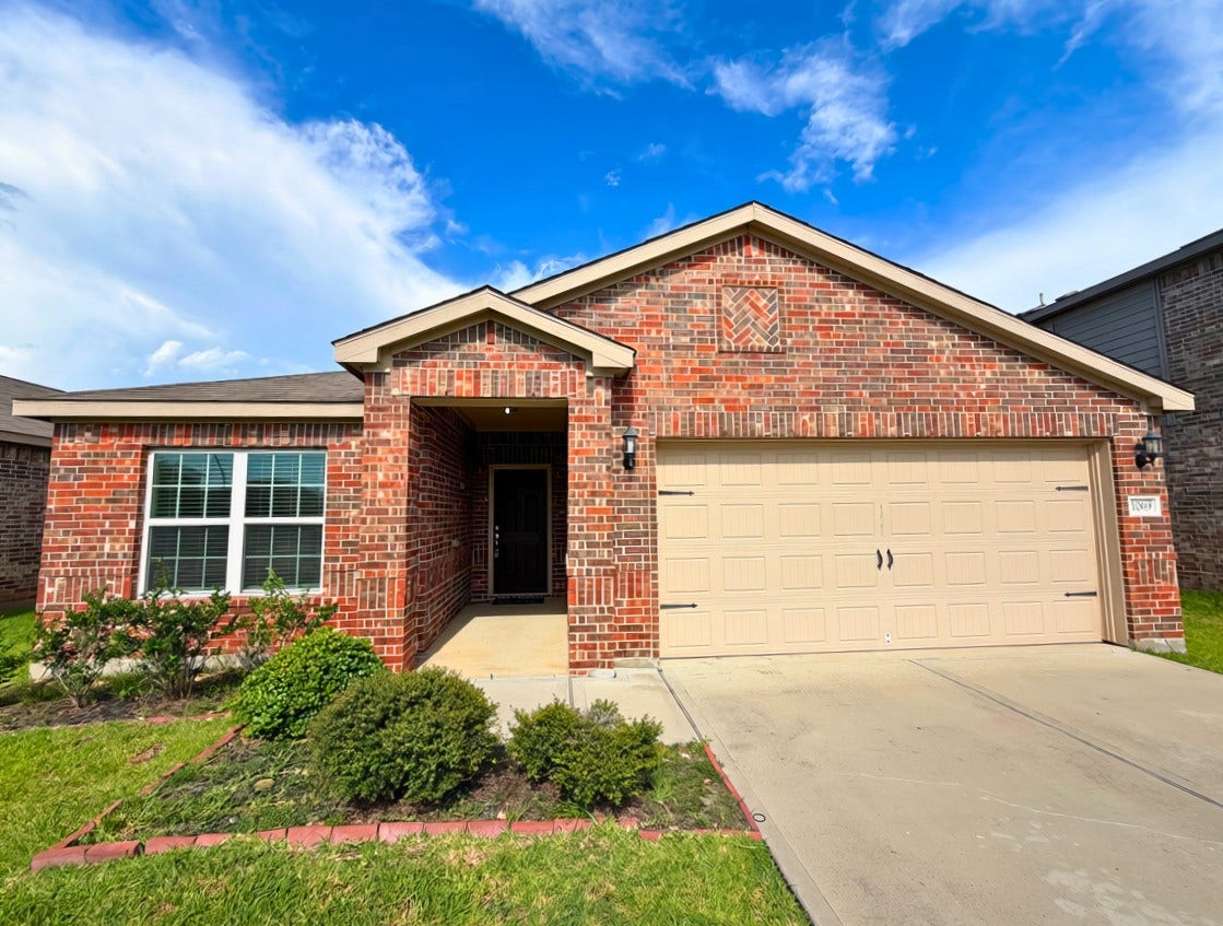 Charming brick home featuring a welcoming front porch, manicured landscaping, and a spacious two-car garage.