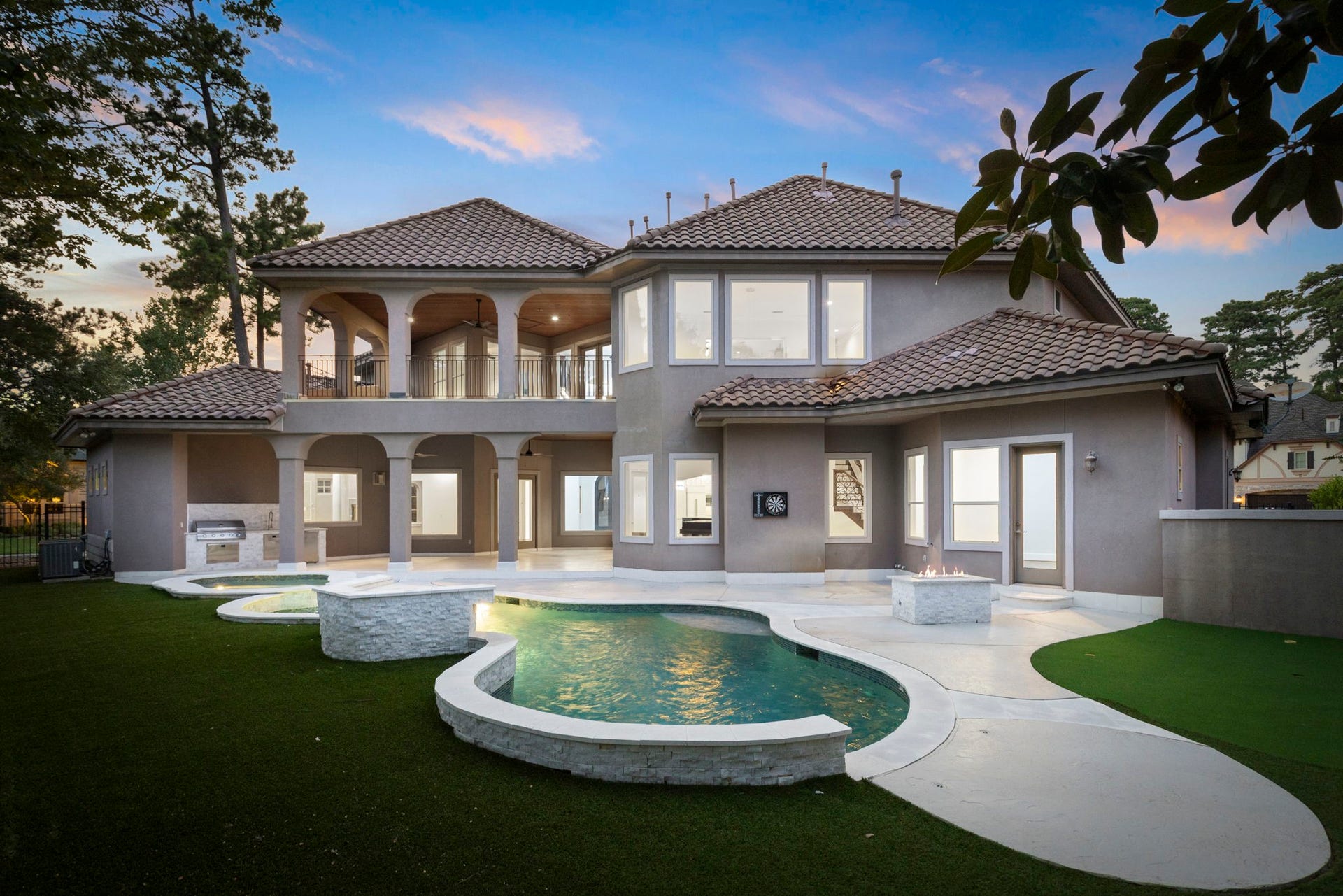 47 Hunnewell Way, The Woodlands, TX 77382 Backyard features a private retreat-style pool/spa with waterfall feature, firepit and updated surround and patio.