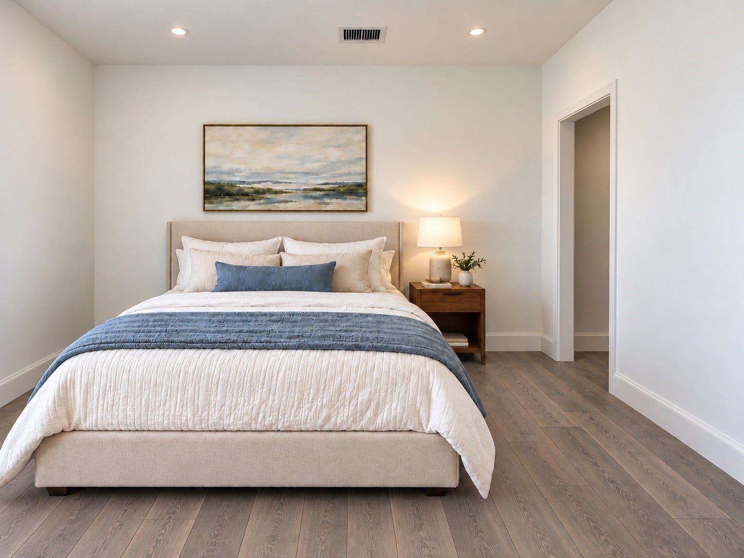 6031 Beall Street, Houston, TX 77091 Step into this inviting bedroom featuring a soothing neutral color palette, beautiful wood-look flooring, and a bright, airy atmosphere. The spacious layout comfortably accommodates a large upholstered bed, complemented by elegant bedding, warm wood furnishings, and tasteful wall artwork. Recessed ceiling lighting provides a clean, modern finish, while crisp white walls create a timeless backdrop. These photos have been virtually rendered for visual reference.