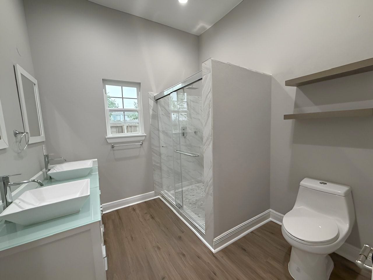 1517 COLORADO Street, Houston, TX 77007 Spacious bathroom featuring a glass-enclosed walk-in shower with marble-look tile surround, modern fixtures, natural lighting, and convenient open shelving.