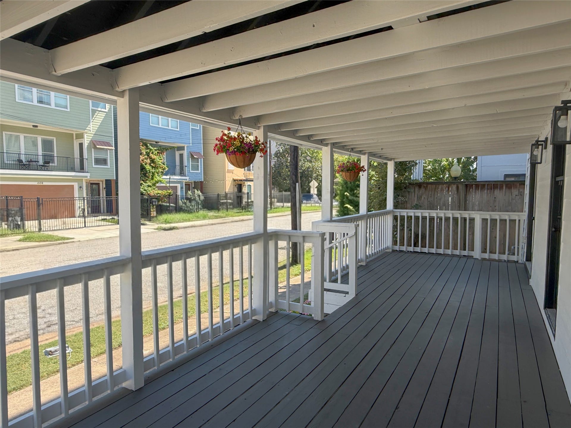 1517 COLORADO Street, Houston, TX 77007 Generously sized outdoor living space featuring painted wood decking, exposed ceiling beams, and hanging flower baskets.