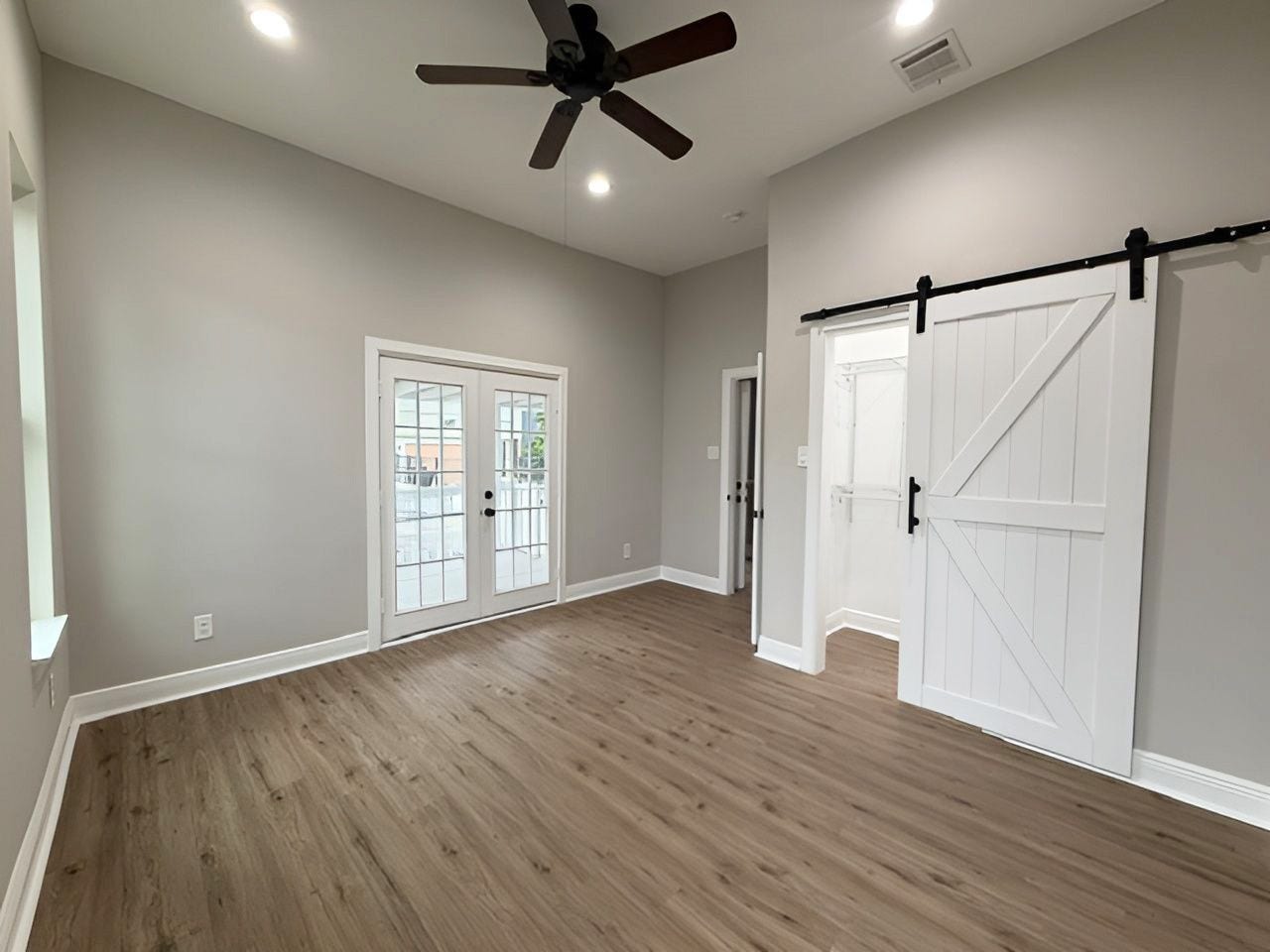 1517 COLORADO Street, Houston, TX 77007 This angle showcases the sliding barn door closet, attractive flooring, and spacious layout, with French doors providing additional natural light.