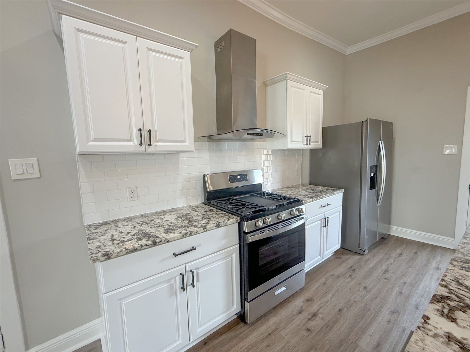 1517 COLORADO Street, Houston, TX 77007 Beautifully appointed kitchen featuring white shaker-style cabinetry, granite countertops, subway tile backsplash, NEW stainless steel gas range, coordinating vent hood, and refrigerator.