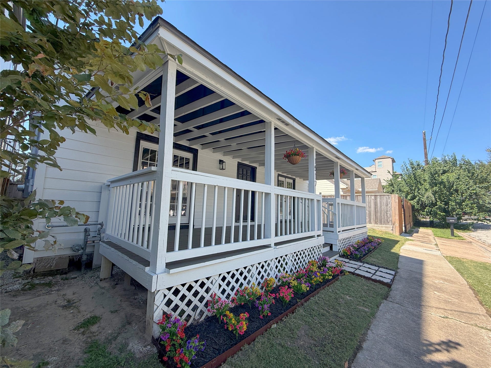 1517 COLORADO Street, Houston, TX 77007 Attractive side perspective highlighting the home's classic exterior, decorative latticework, and colorful flower beds lining the porch.