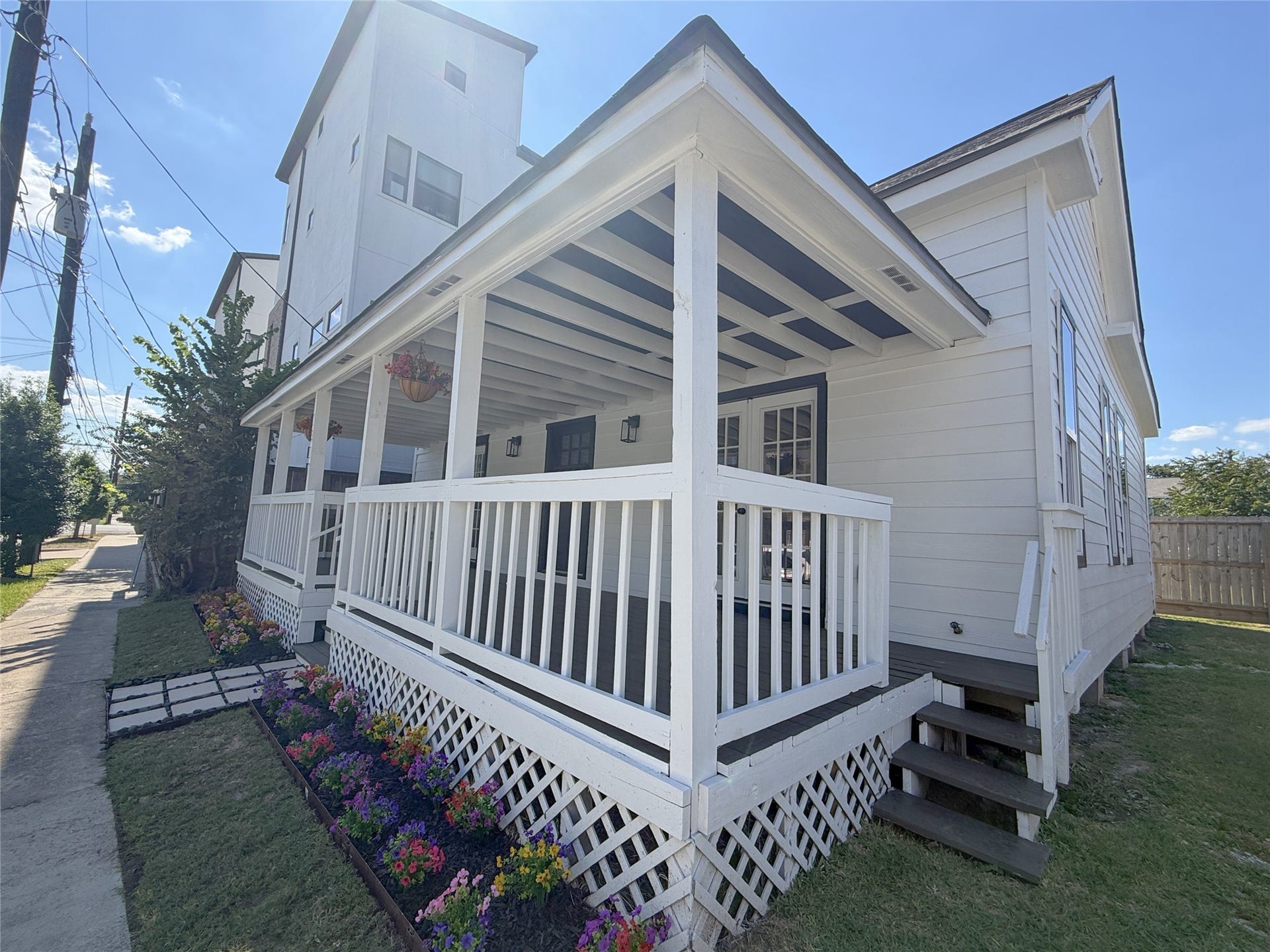 1517 COLORADO Street, Houston, TX 77007 Angled view showcasing the home's expansive covered porch, crisp white railings, and convenient side access.