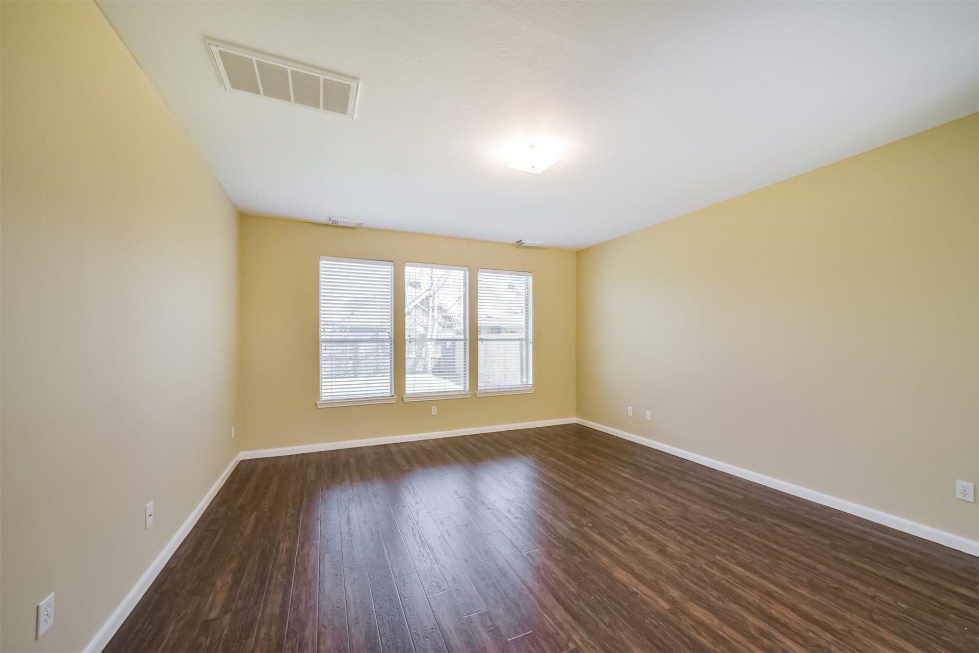Main-level primary bedroom with natural light from three windows facing the yard.