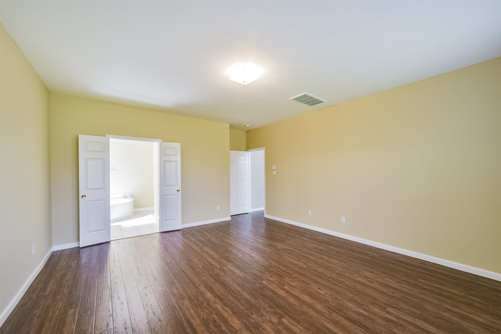 Primary bedroom with French doors to the ensuite bath.