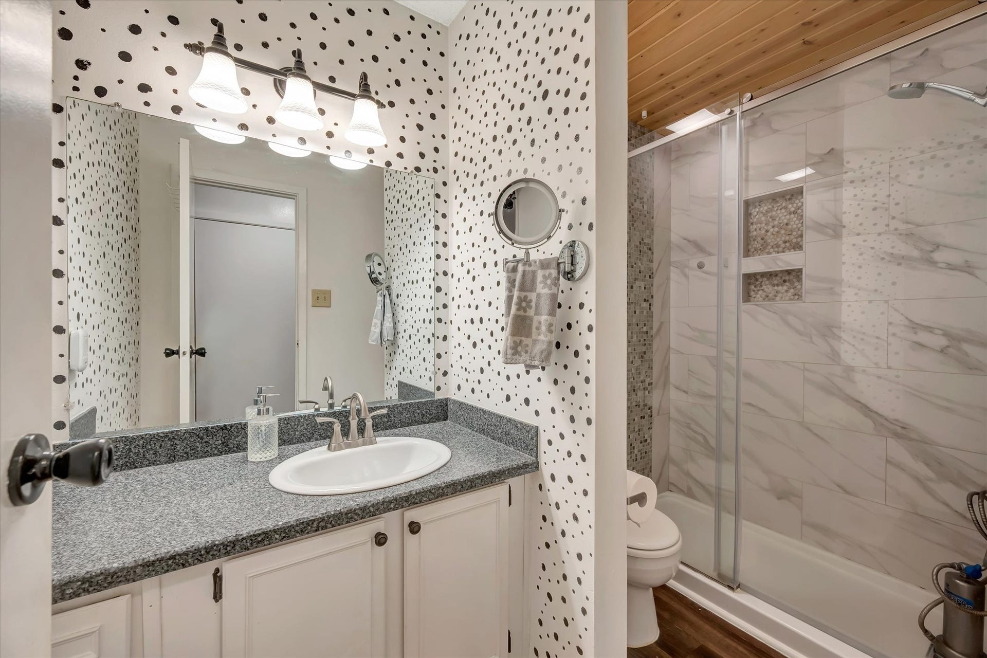 7071 N Holiday Drive, Galveston, TX 77550 Bathroom with a vanity, patterned wall detail and a glass-enclosed shower.