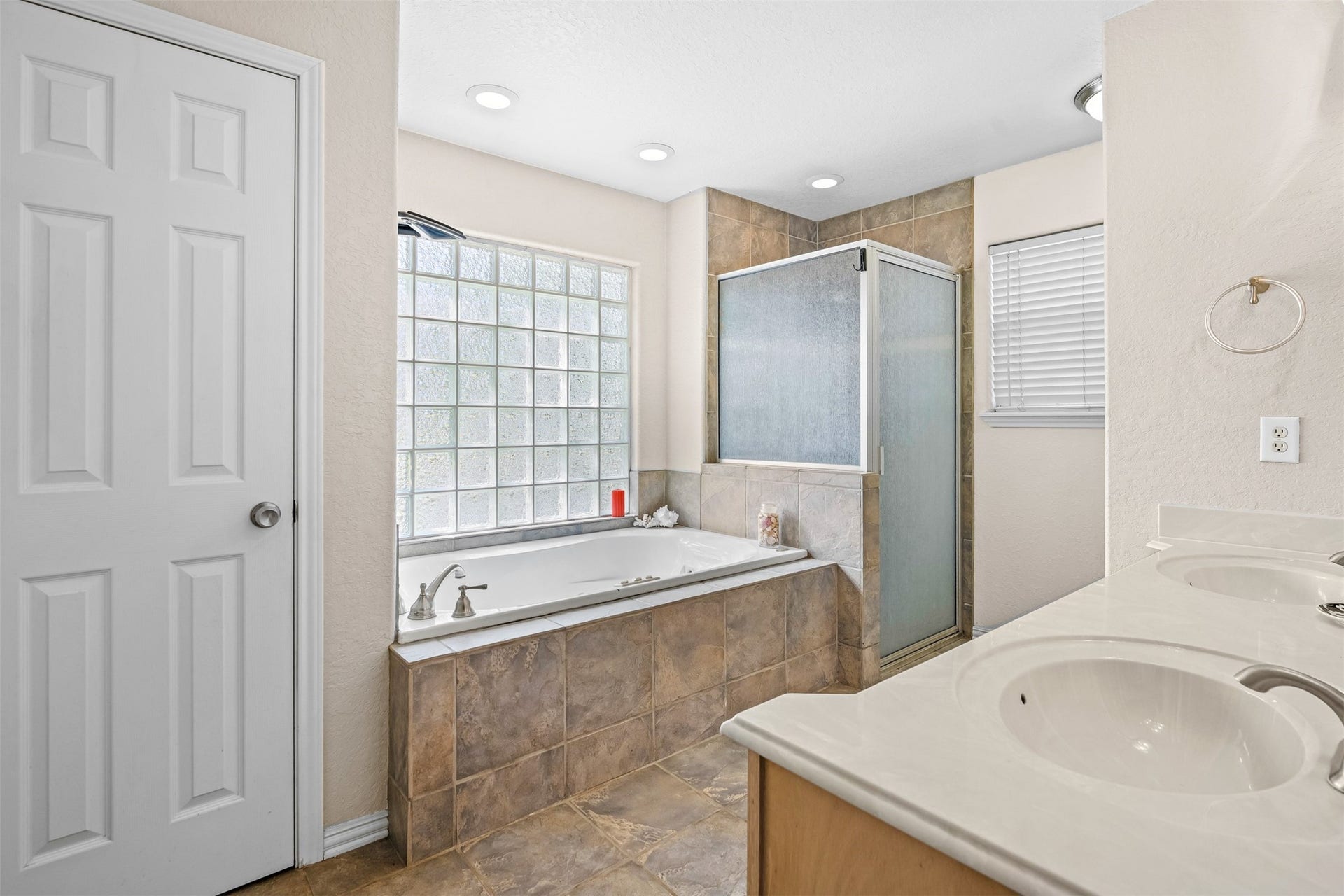 The primary bathroom has an oversized jetted tub with glass block obscure window and separate walk in shower.