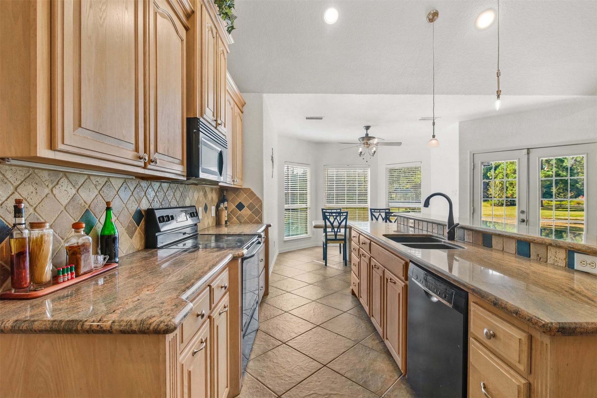 This lovely kitchen features granite countertops, maple cabinets, tile floors and decorative tile backsplash.