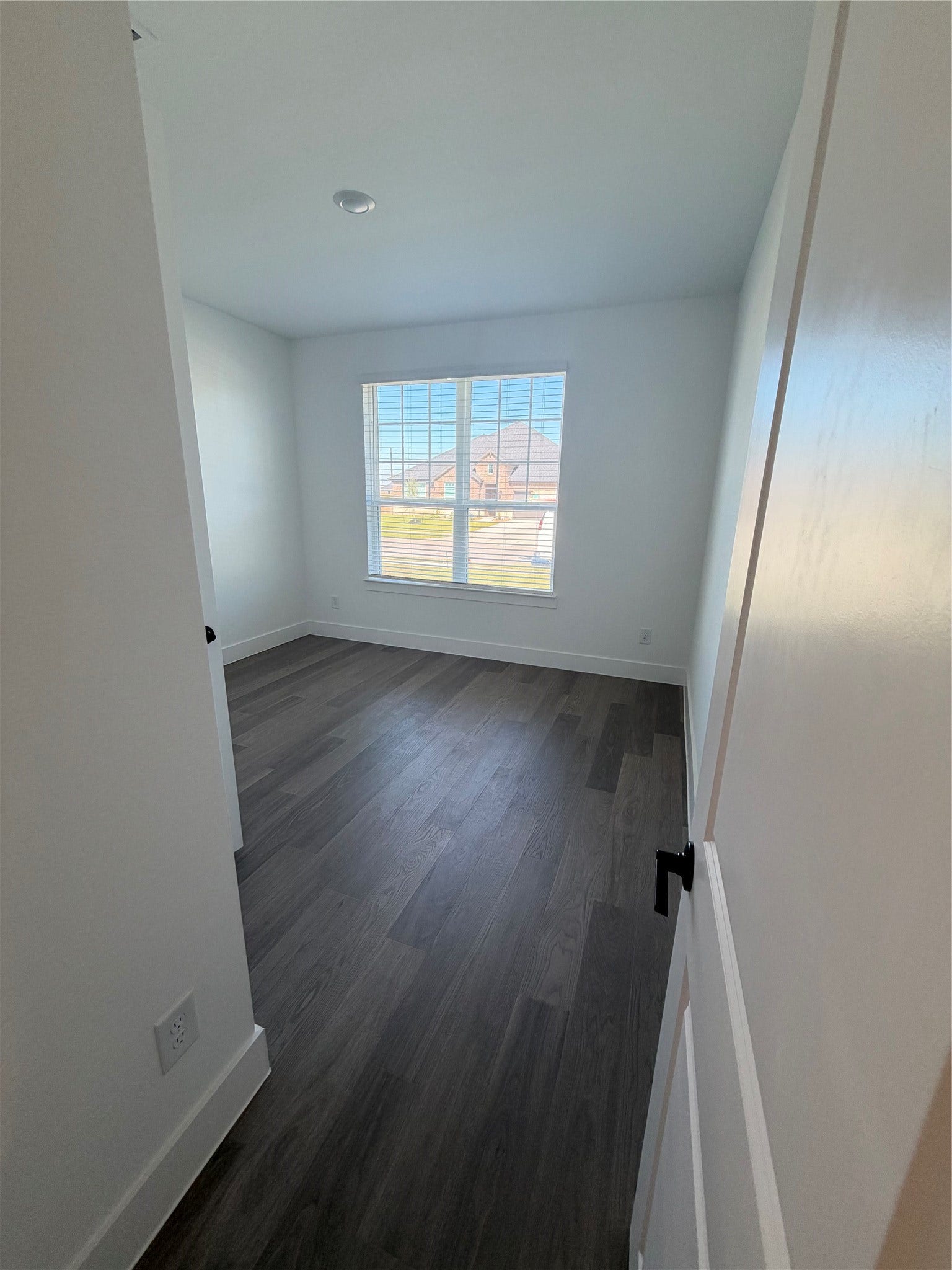 3428 Summercrisp Hollow Lane, Pearland, TX 77581 Bright and inviting bedroom featuring sleek dark wood flooring and a large window offering ample natural light.