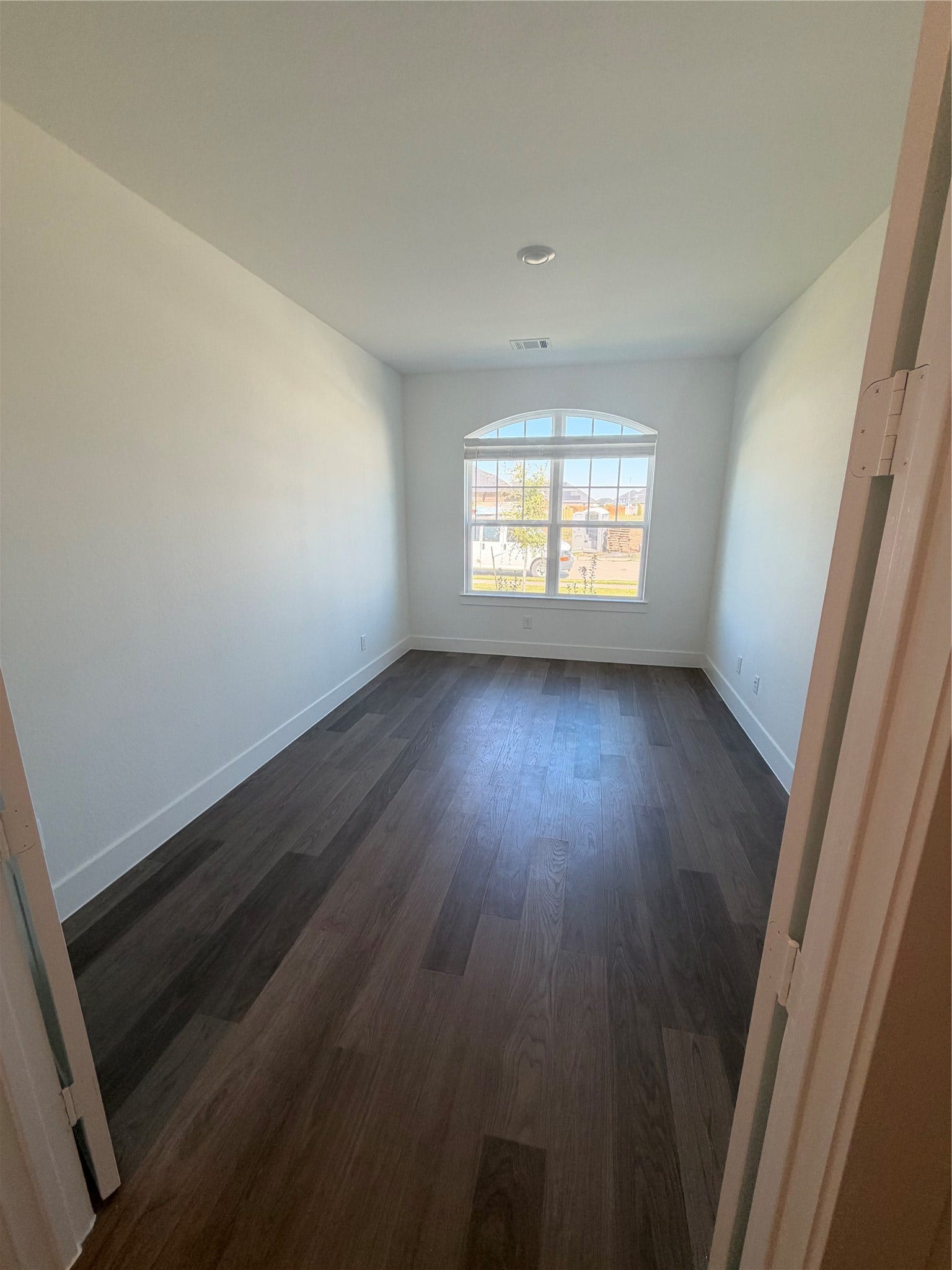 3428 Summercrisp Hollow Lane, Pearland, TX 77581 Bright office/den with elegant, dark wood flooring and a large arched window providing ample natural light.