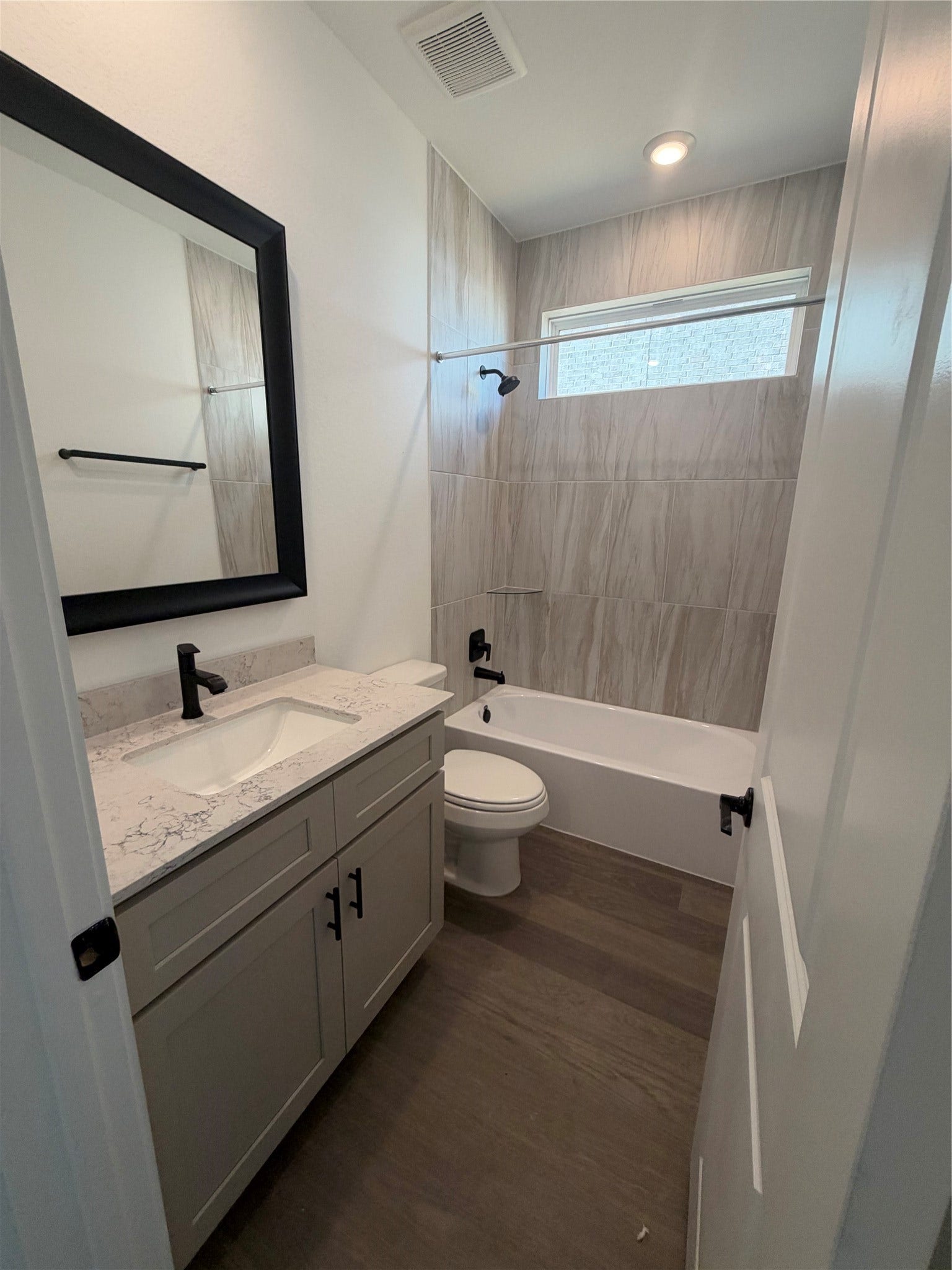 3428 Summercrisp Hollow Lane, Pearland, TX 77581 Stylish bathroom featuring a modern vanity with a sleek black framed mirror, elegant marble countertop, and a sophisticated tub with contemporary tile surround.