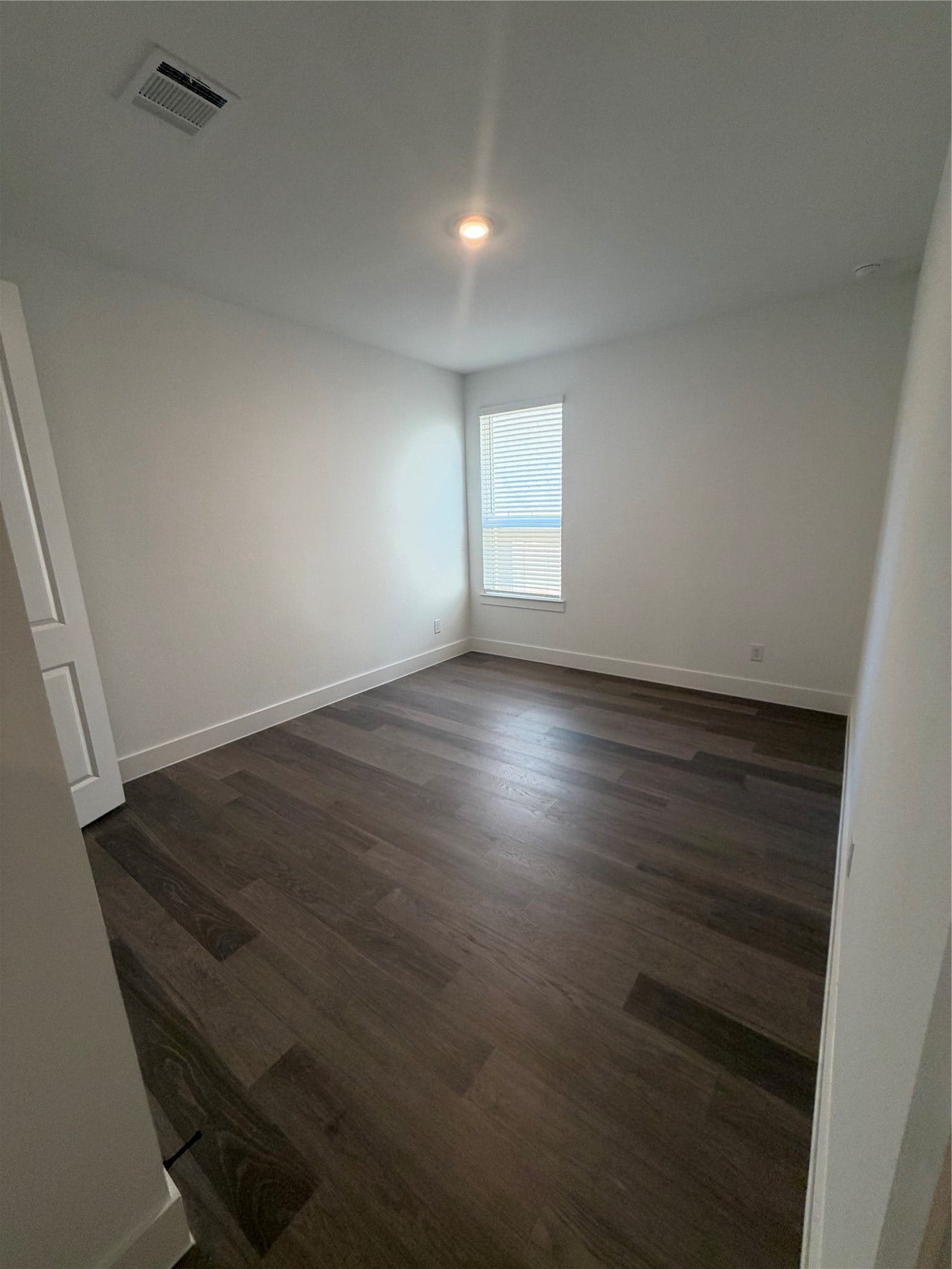 3428 Summercrisp Hollow Lane, Pearland, TX 77581 Bright, minimalist bedroom with sleek dark hardwood floors and a large window for natural light.