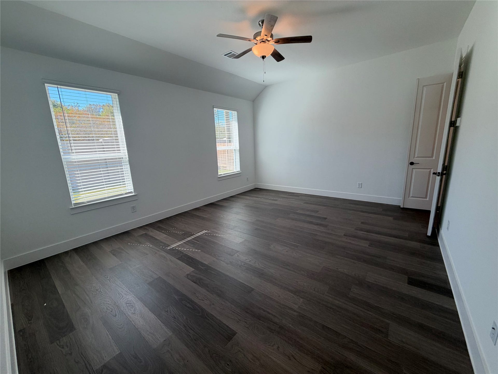 3428 Summercrisp Hollow Lane, Pearland, TX 77581 Spacious primary bedroom featuring rich, dark wood flooring, large windows for natural light, and a ceiling fan for comfort.