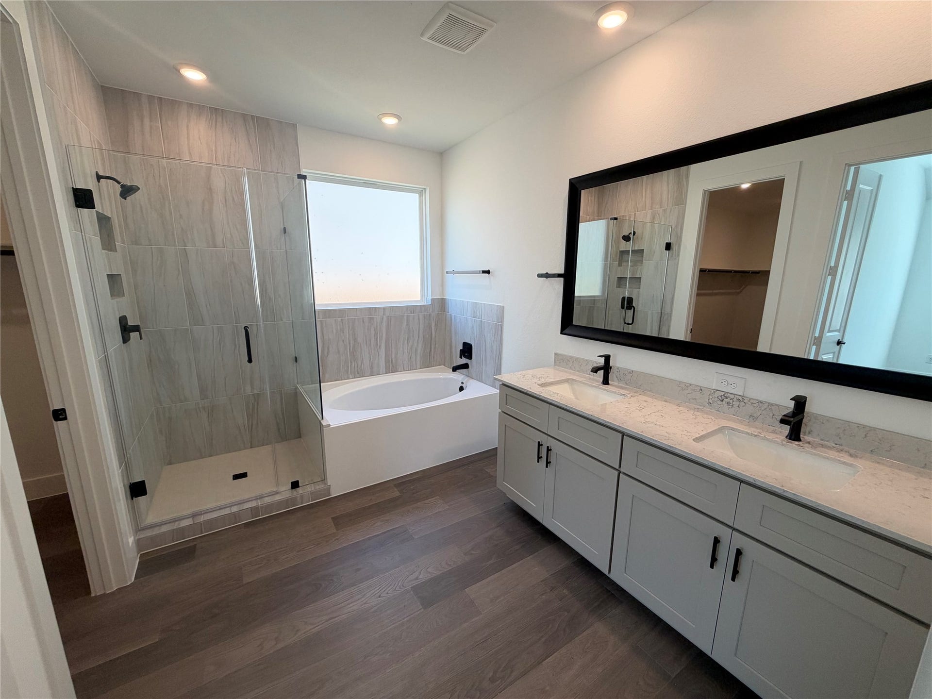 3428 Summercrisp Hollow Lane, Pearland, TX 77581 Elegant bathroom featuring a spacious glass-enclosed shower, a luxurious soaking tub, and a dual-sink vanity with sleek fixtures and ample storage.