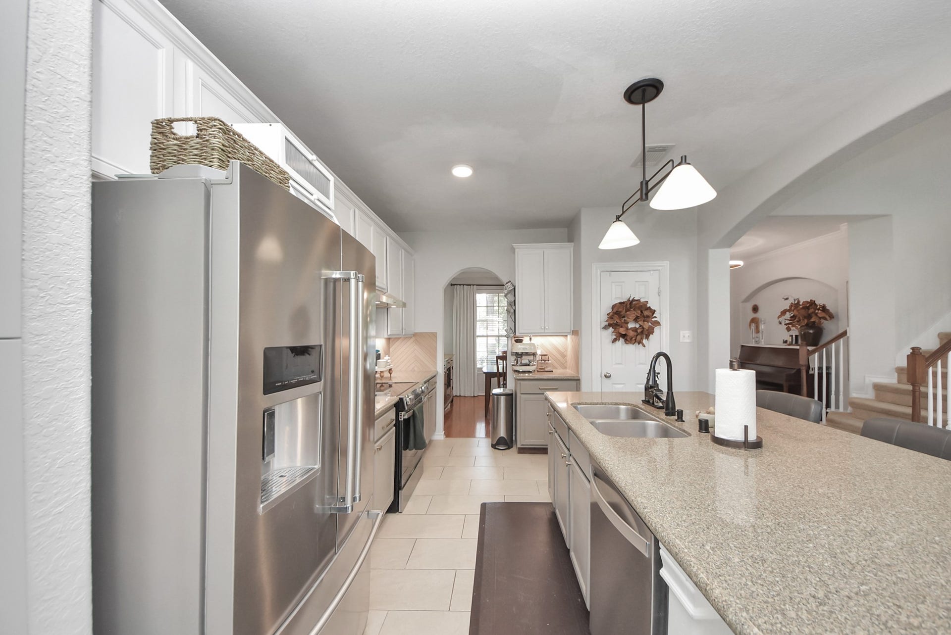 A well-appointed kitchen features crisp white cabinetry, granite countertops, stainless steel appliances, and a generous island with bar seating.