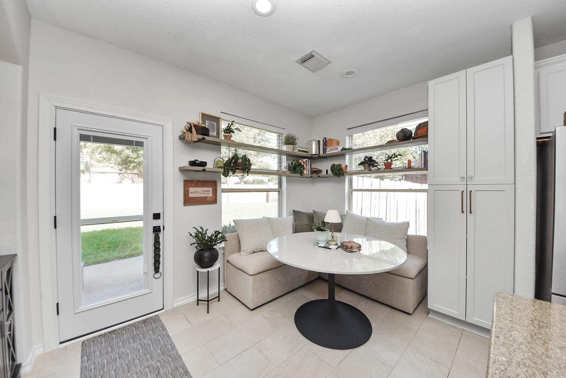 A cozy breakfast nook with built-in banquette seating, abundant natural light, and stylish open shelving makes everyday meals a pleasure.