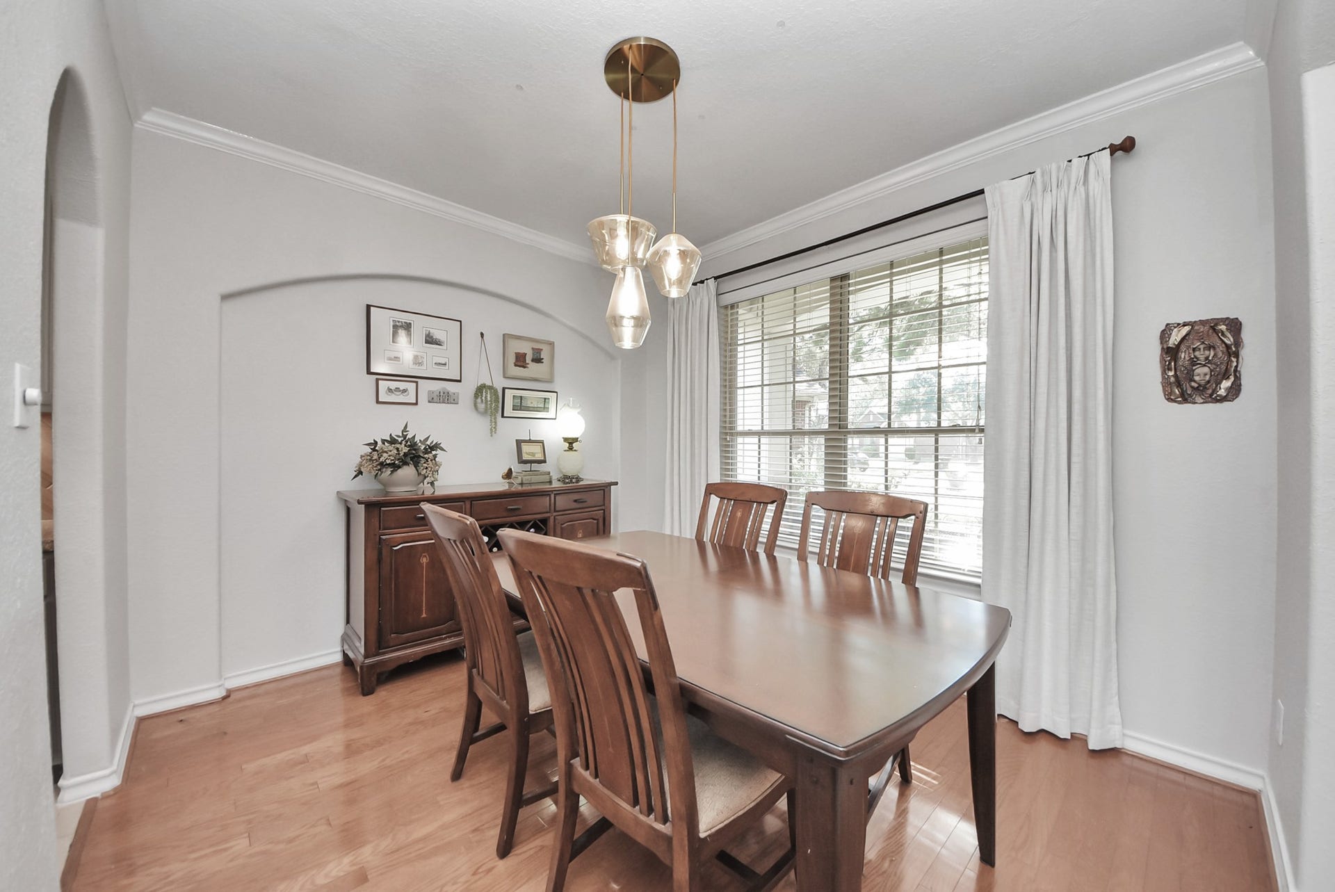 Gather for memorable meals in this bright dining space featuring a large window, elegant pendant lighting, and warm wood flooring.