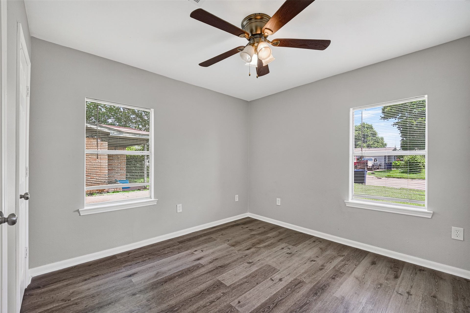 3408 Palm Avenue, Texas City, TX 77590 This room features two large windows for natural light, fresh gray walls, modern wood flooring, and a ceiling fan, creating a bright and inviting space.