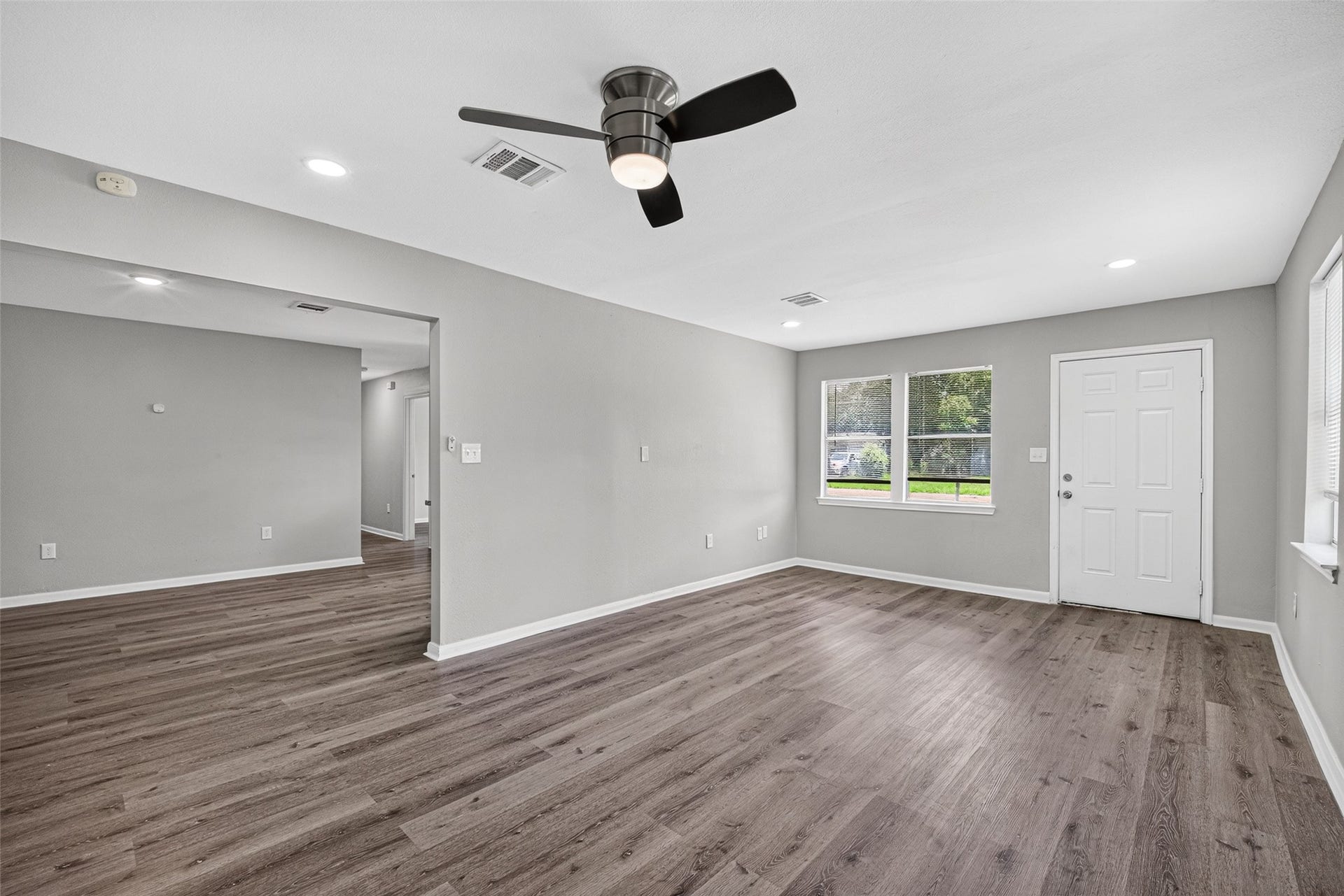 3408 Palm Avenue, Texas City, TX 77590 Experience a bright and open living area with sleek wood flooring and neutral gray walls. Enjoy abundant natural light from large windows, complemented by recessed lighting and a ceiling fan. This versatile space seamlessly connects to an additional area, perfect for various setups.