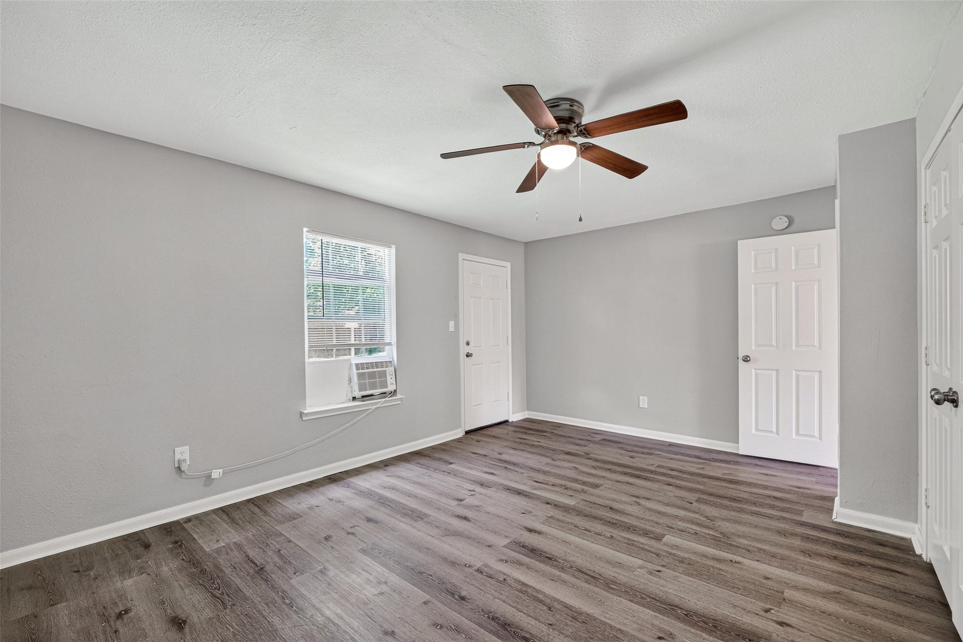 3408 Palm Avenue, Texas City, TX 77590 This inviting room boasts a chic gray palette, wood-style flooring, and a ceiling fan. Enjoy abundant natural light and comfort from the window AC unit.