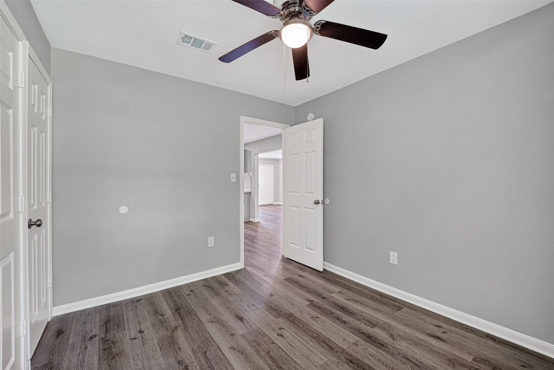 3408 Palm Avenue, Texas City, TX 77590 This room features gray walls, wood flooring, a ceiling fan with lights, and a white door leading to another area. It's bright and modern, perfect for a bedroom or office space.