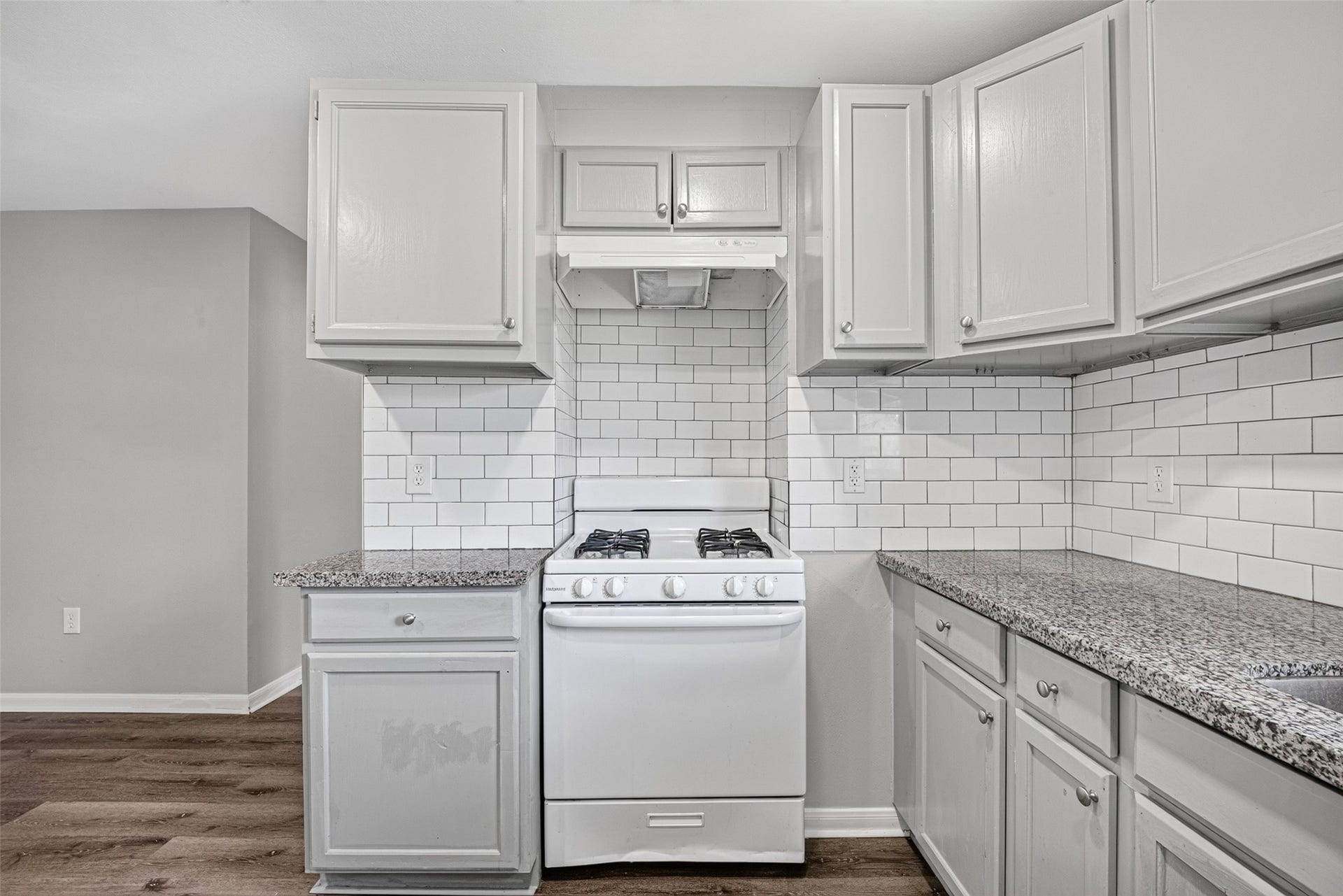 3408 Palm Avenue, Texas City, TX 77590 This kitchen features modern white cabinetry, a gas stove, and sleek granite countertops. The subway tile backsplash adds a classic touch, complementing the neutral color palette.