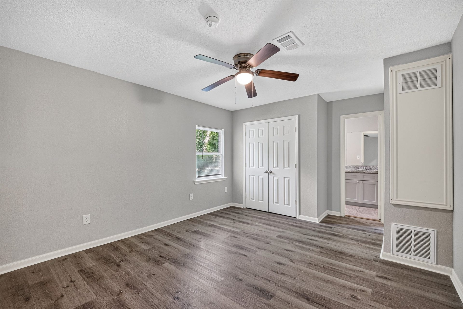 3408 Palm Avenue, Texas City, TX 77590 This room features fresh gray walls, wood-look flooring, and a ceiling fan. It has a window for natural light, a double-door closet, and an adjoining bathroom.
