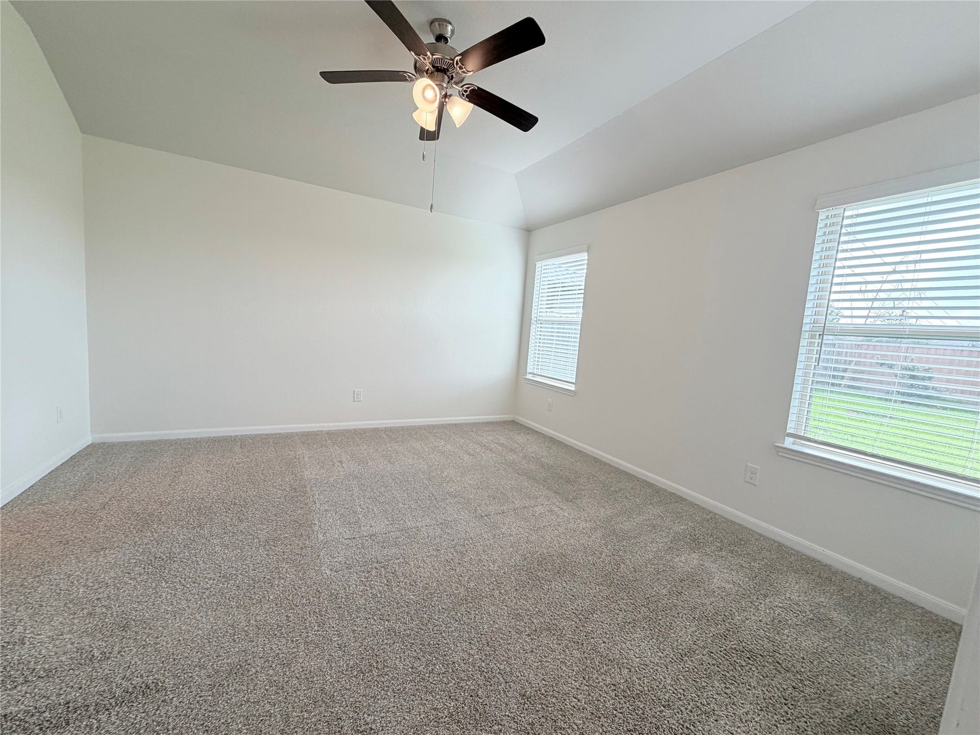 Private primary suite features large windows overlooking the backyard.