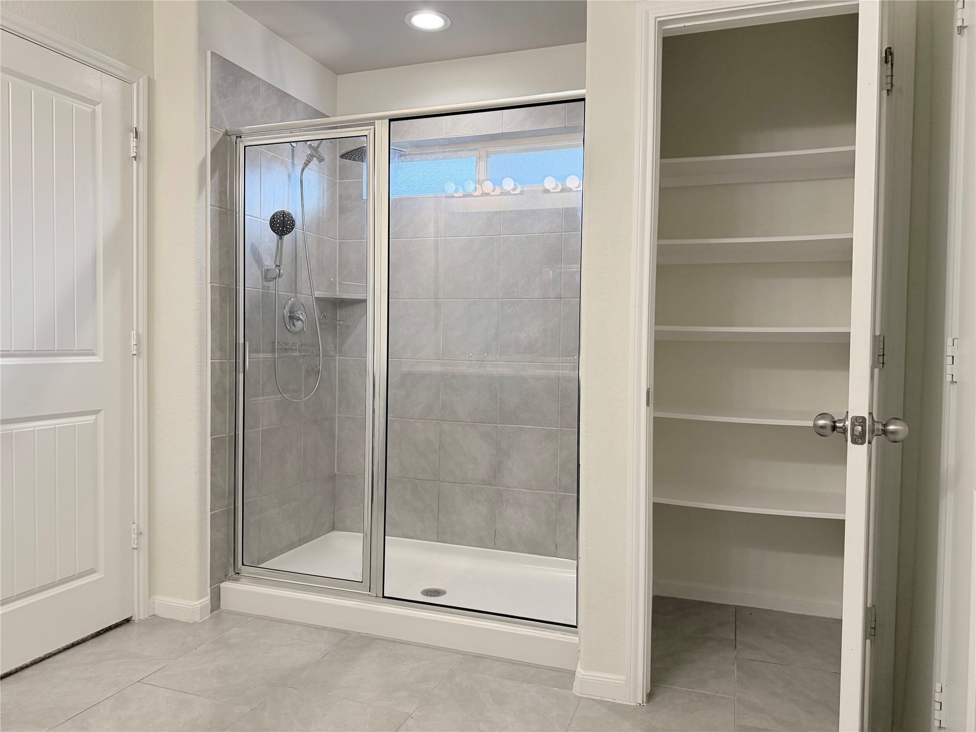 Spacious walk-in shower with built-in shelving and adjacent linen storage.