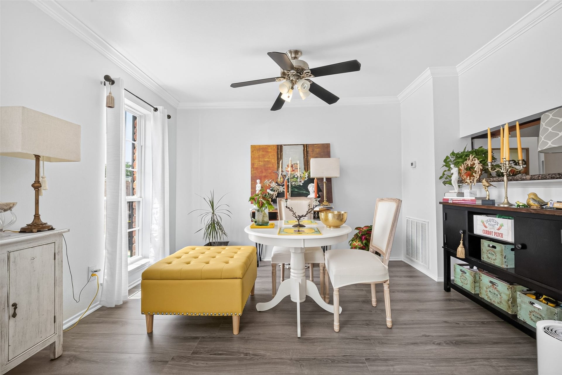 6402 Del Monte Drive, #65, Houston, TX 77057 Bright and inviting dining area with modern decor. Features a ceiling fan, large windows, and light wood flooring. Accented with a yellow ottoman and white furniture, the space offers a cozy yet elegant atmosphere.