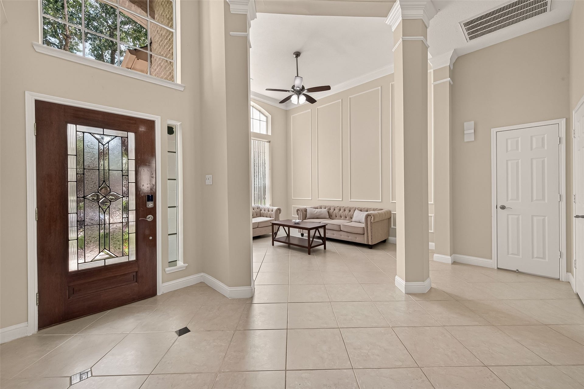 2002 Thorncrest Court, Sugar Land, TX 77479 Elegant entryway with a decorative glass front door, leading into a spacious living area featuring high ceilings, classic columns, and large windows for abundant natural light.