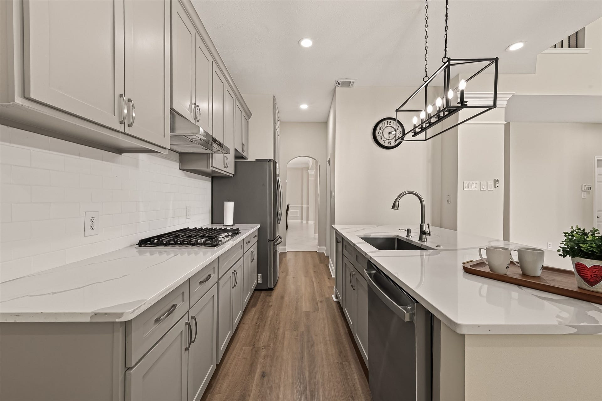 2002 Thorncrest Court, Sugar Land, TX 77479 Sleek modern kitchen featuring elegant cabinetry, a spacious island with a sink, and high-end stainless steel appliances, complemented by warm wood flooring and stylish lighting.